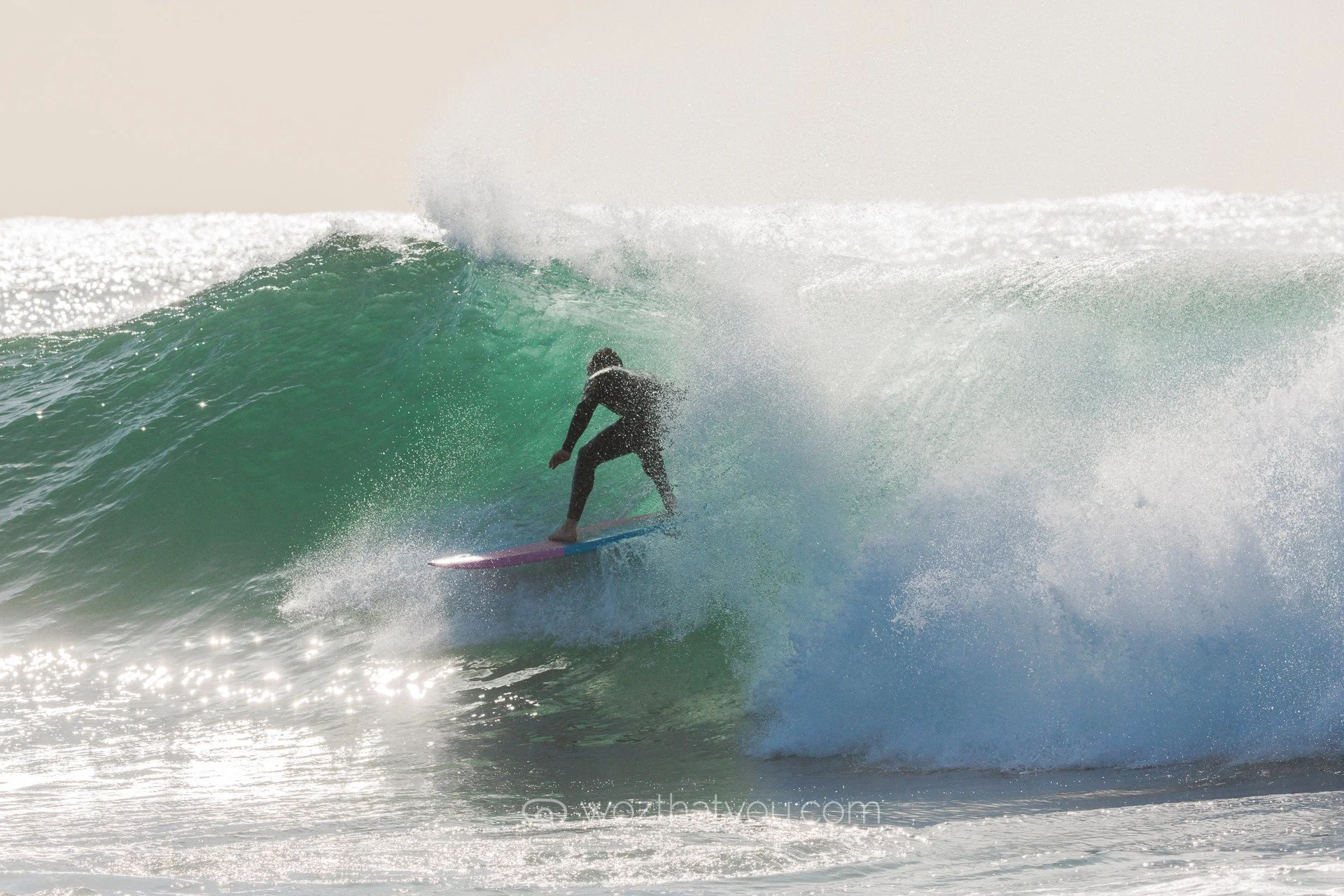 A person surfing on a large wave in the ocean during daytime.
