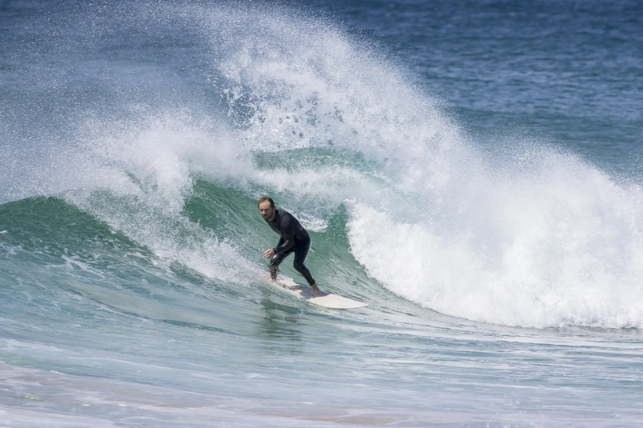 A man surfing on a wave in the ocean, wearing a wetsuit.