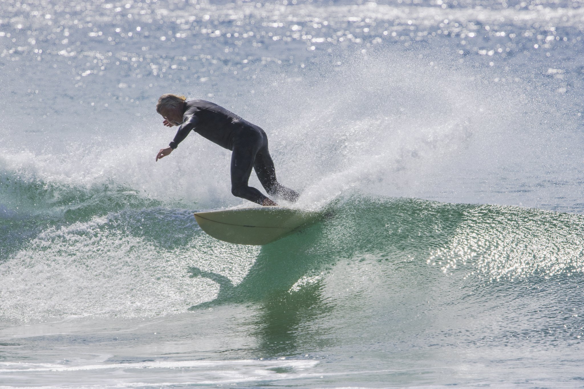 A person surfing on a small wave in the ocean, wearing a wetsuit.