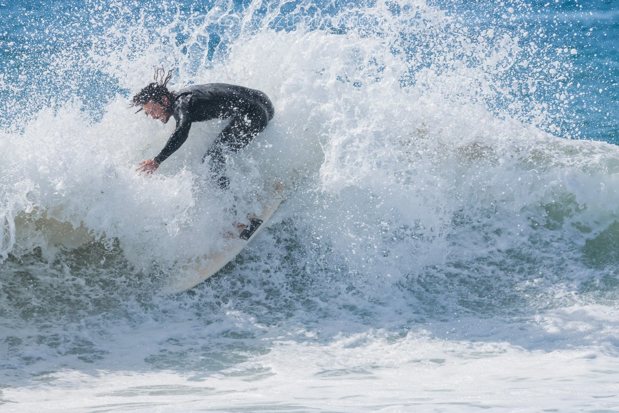 Person in black wetsuit surfing on a wave