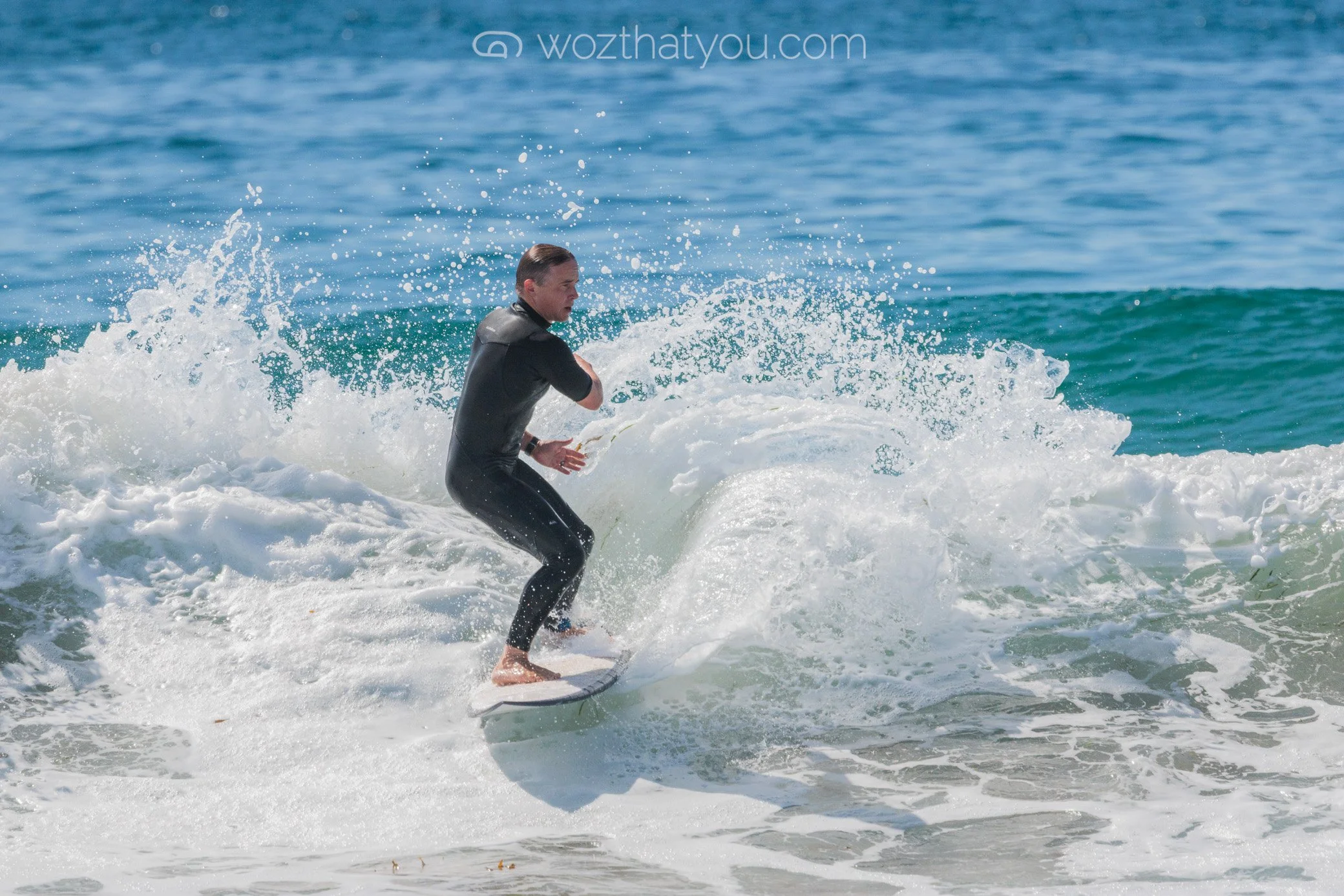 A man in a wetsuit surfing on a wave in the ocean.