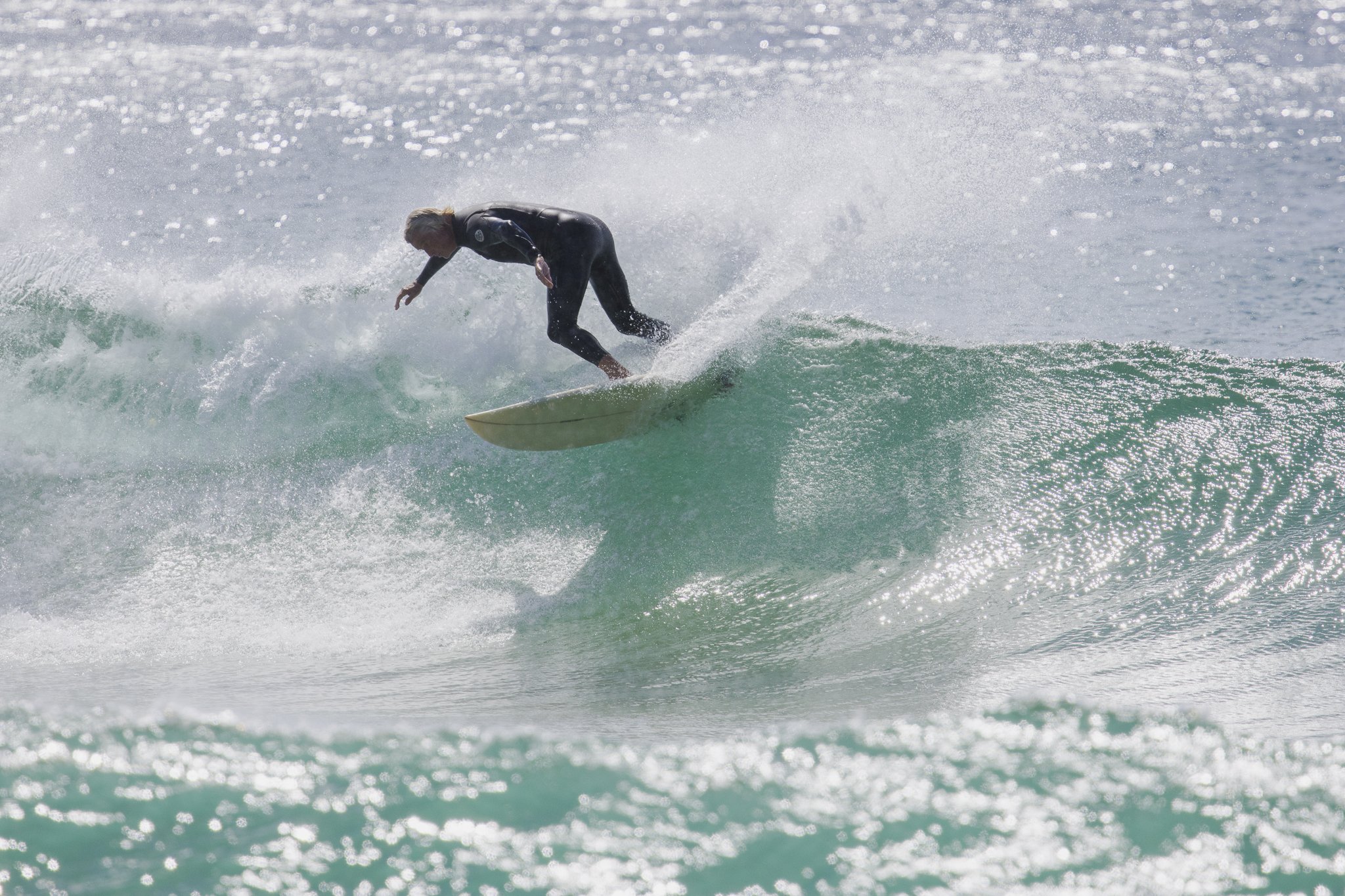 A person in a wetsuit surfing on a wave in the ocean.