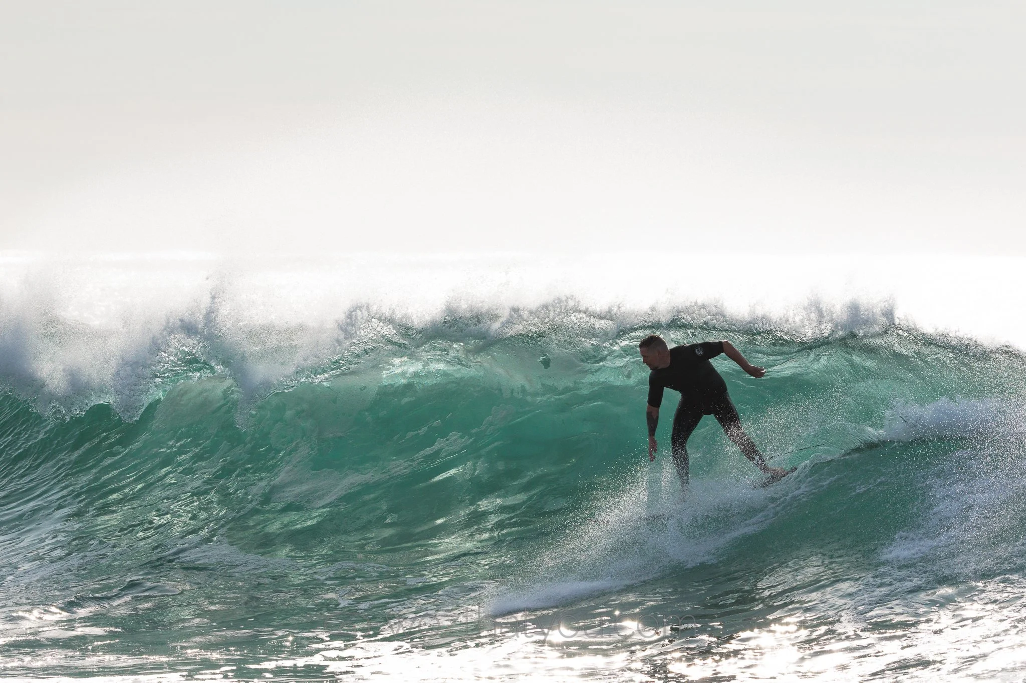 A man surfing on a large ocean wave during daytime
