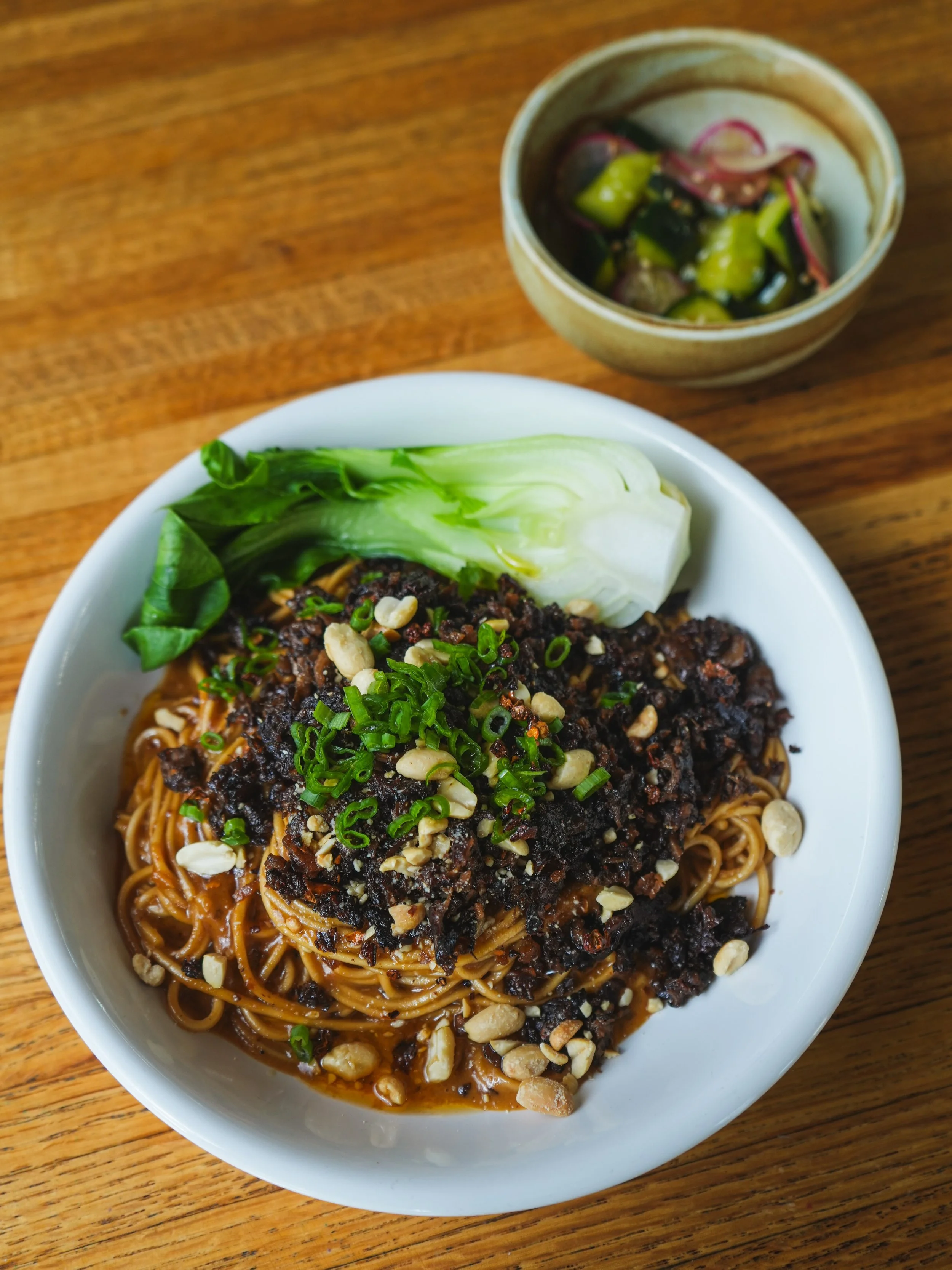 Stop by today for the Dan Dan Noodles!!! 🤩🍜🌱🔥Wheat Noodles with spicy Sichuan peanut sauce topped with tofu mince, crushed peanuts &amp; green onions. Served with steamed organic Bok Choy and side of Cucumber Salad. Available until 8PM.