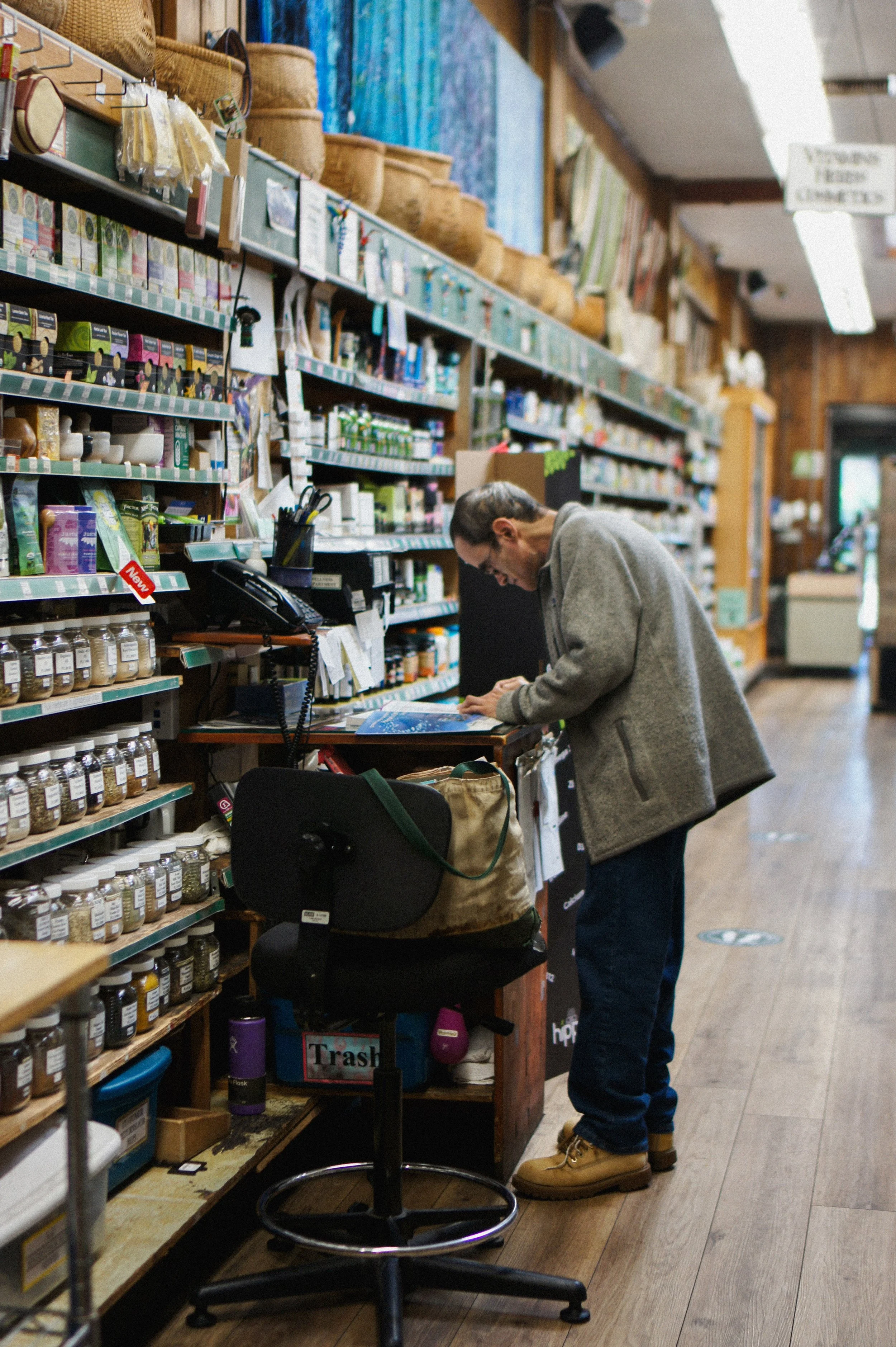 A basket filled with various skincare, wellness, and personal care products, including foot masks, hair styling tools, bath salts, homeopathic lozenges, nail polish, and a soap dish.