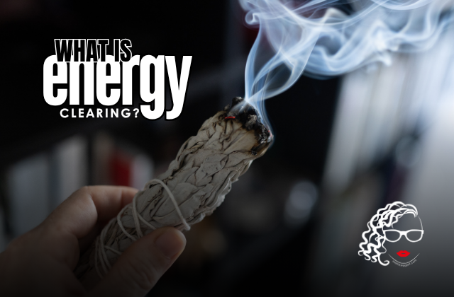 A hand holding a lit bundle of sage that is burning, with smoke rising from it, against a blurred background. Text reads 'What is energy clearing?'