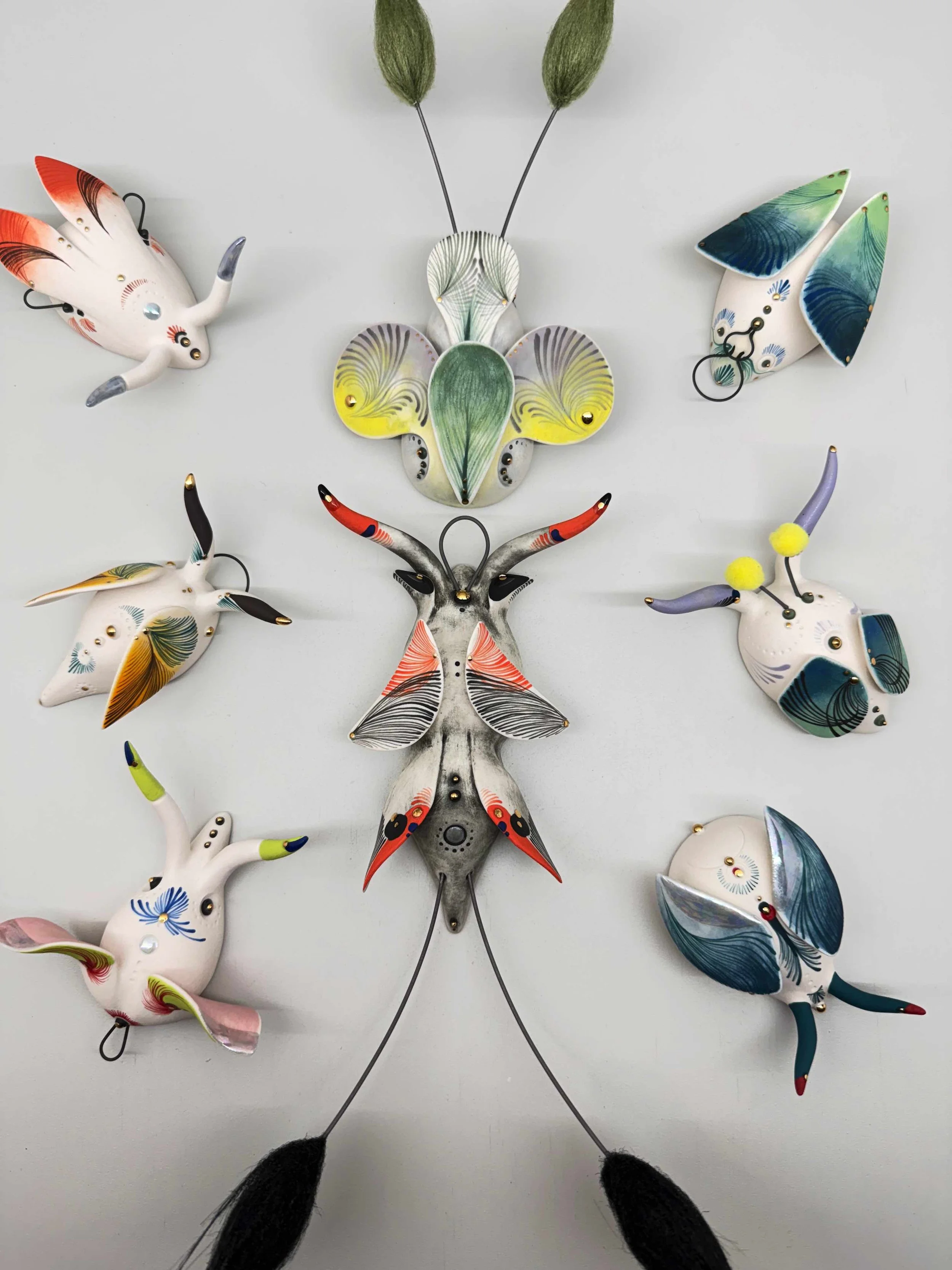 Interior decor scene with a mint green sideboard, colorful abstract painting, a modern gold table lamp, three stacked books, two candles in glass holders, tall curtains, and a large potted plant with big green leaves against a dark green wall.