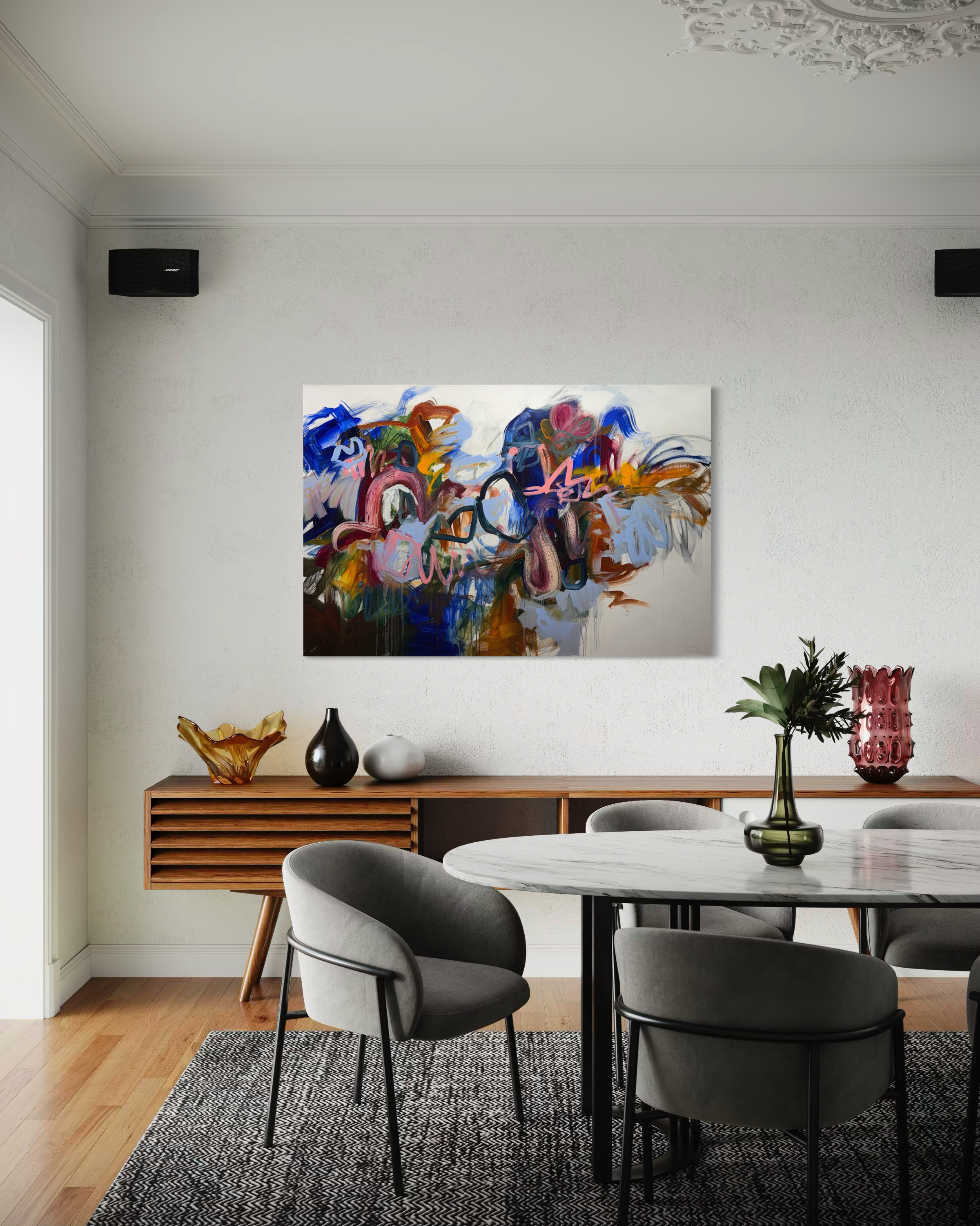 Elegant bedroom with a bed, side tables with lamps, a colorful abstract painting on the wall, a plush armchair with a floral arrangement, and a window with curtains.