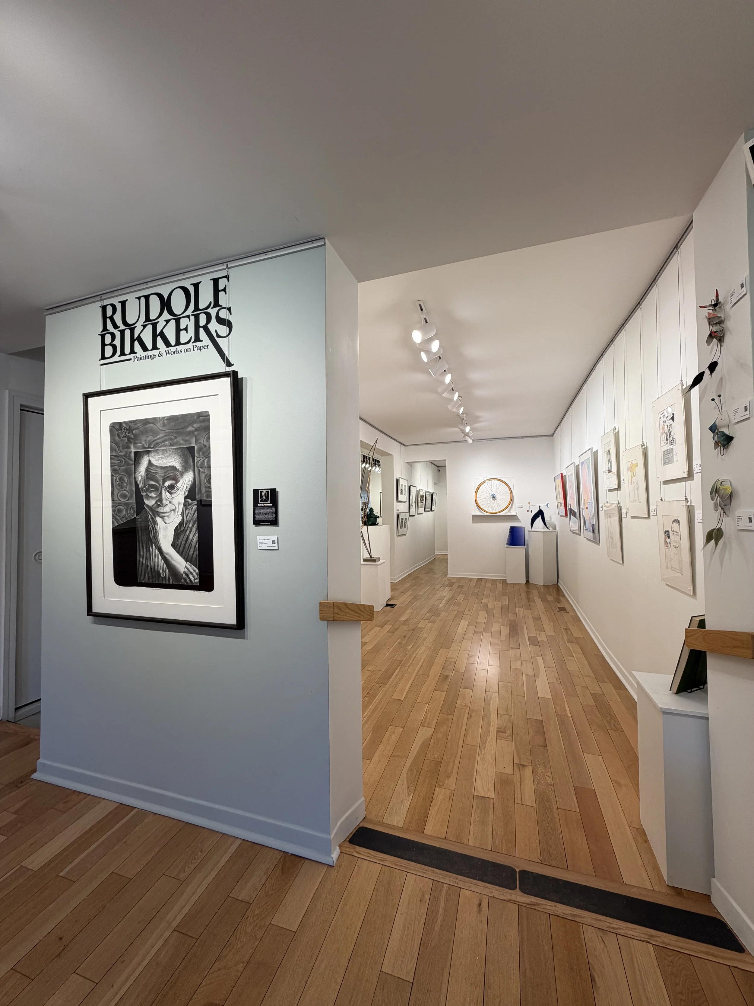 Interior decor scene with a mint green sideboard, colorful abstract painting, a modern gold table lamp, three stacked books, two candles in glass holders, tall curtains, and a large potted plant with big green leaves against a dark green wall.
