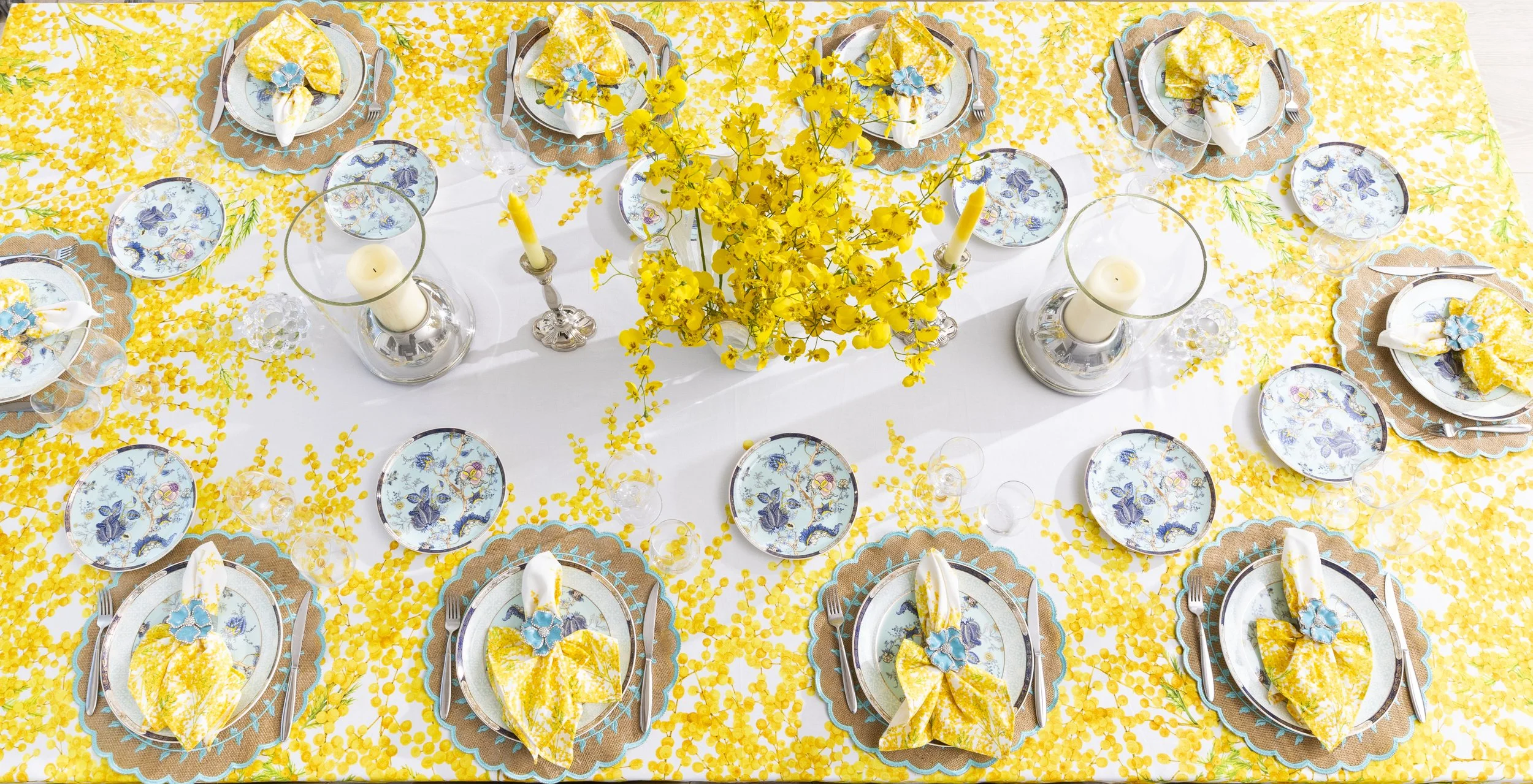 The Mimosa Bloom Tablecloth is a charming addition to your dining decor, perfect for brightening up your space with its vibrant colors. Made from 100% cotton, this tablecloth is not only stylish but also soft and durable. The sunny hues of the mimosa