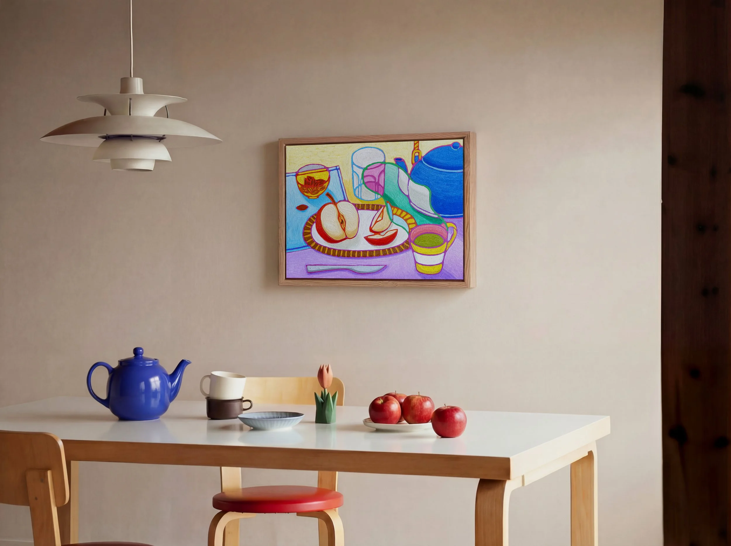 A white dining table with a blue teapot, a small white cup, a small brown cup, and a small plant with a pink flower in a green container. A plate with three red apples is on the table. The background includes a beige wall with a colorful still life p