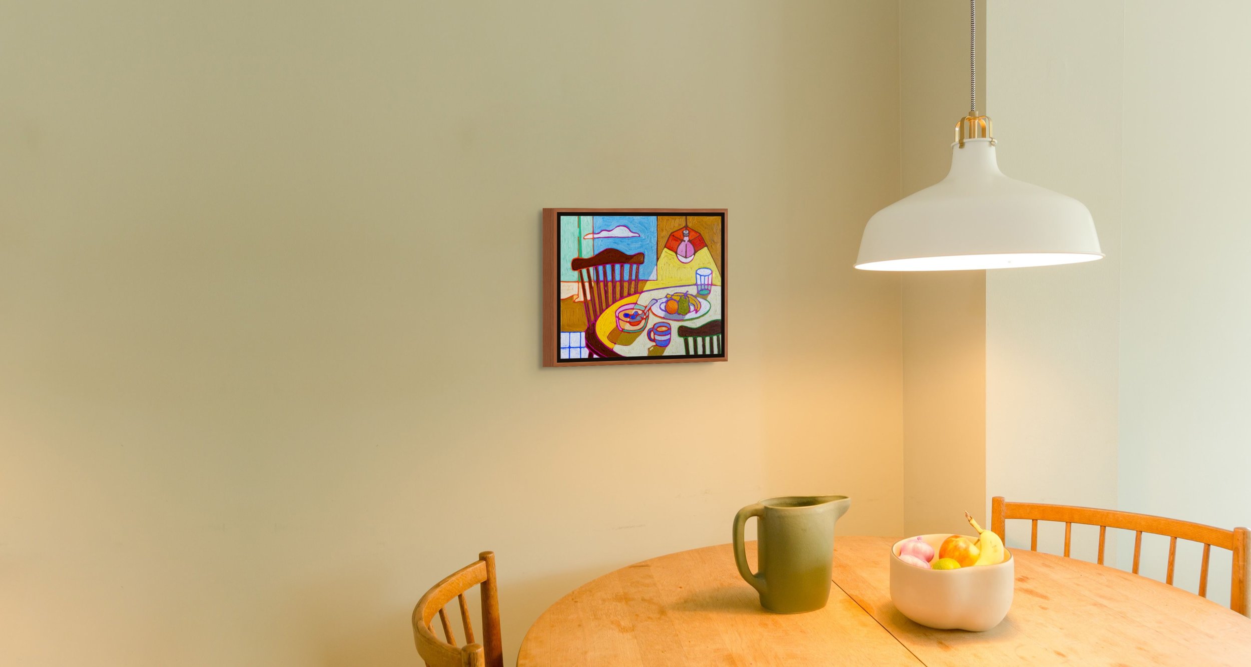 A dining room with a wooden oval table, a green pitcher, a white bowl with fruits, a wooden chair, a white hanging lamp, and a colorful framed painting on a beige wall.