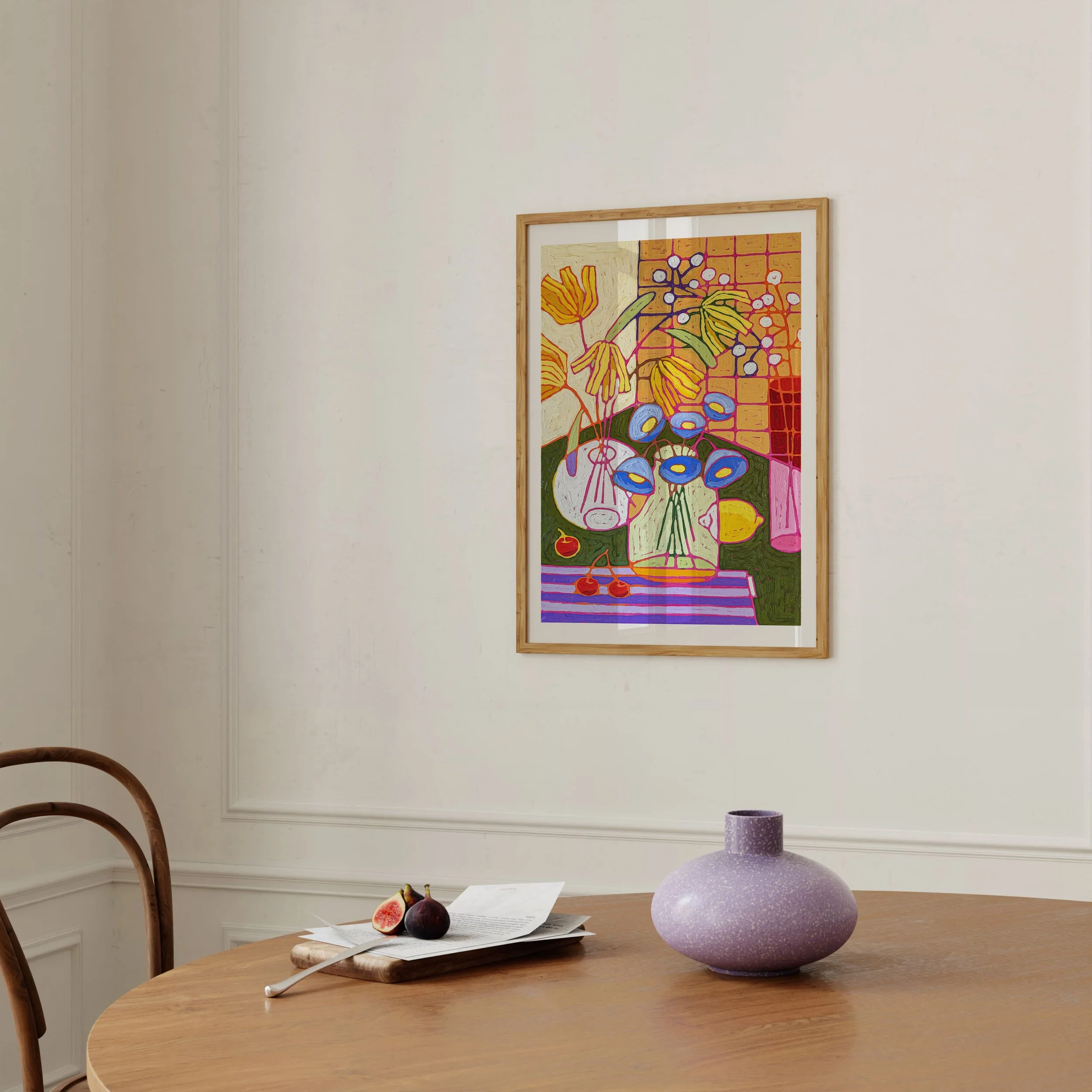 Colorful abstract still life painting of flowers in vases hanging on a white wall, with a round purple vase and a fig with paper on a wooden table in the foreground.