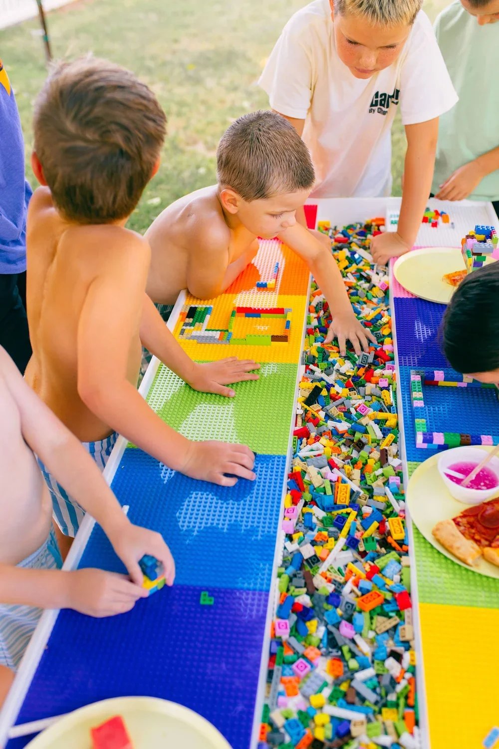 Children playing with LEGO bricks at an outdoor table.