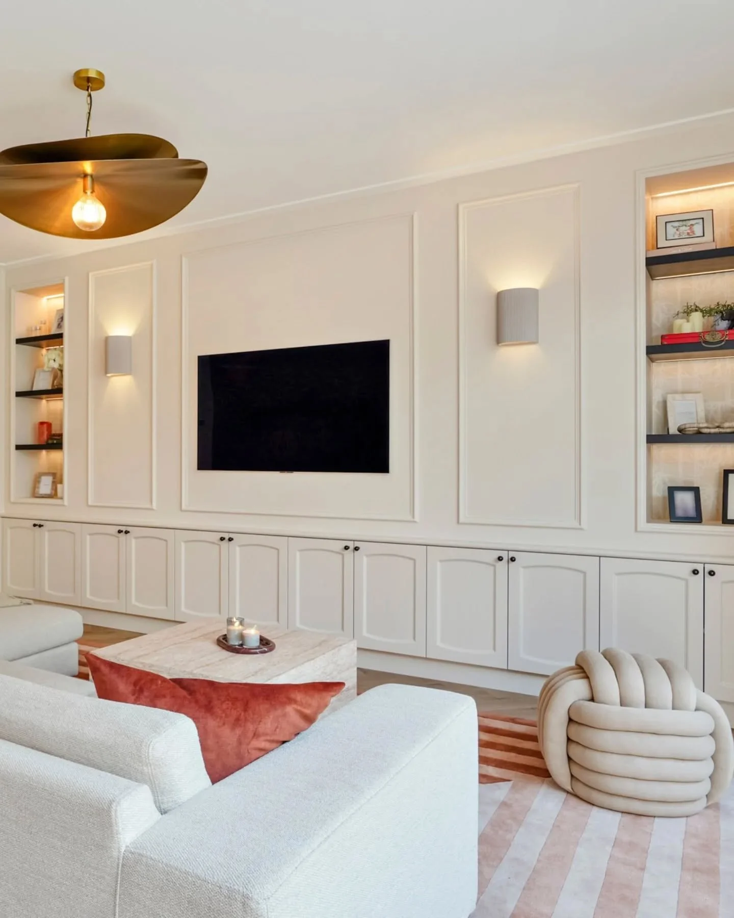 This living space used to be cool blues and whites and was lacking personality and 'chic-ness'! 

We warmed it up with farrow and balls skimming stone walls, a custom storage wall with a pop of black in the shelving and hand painted bamboo wallpaper 