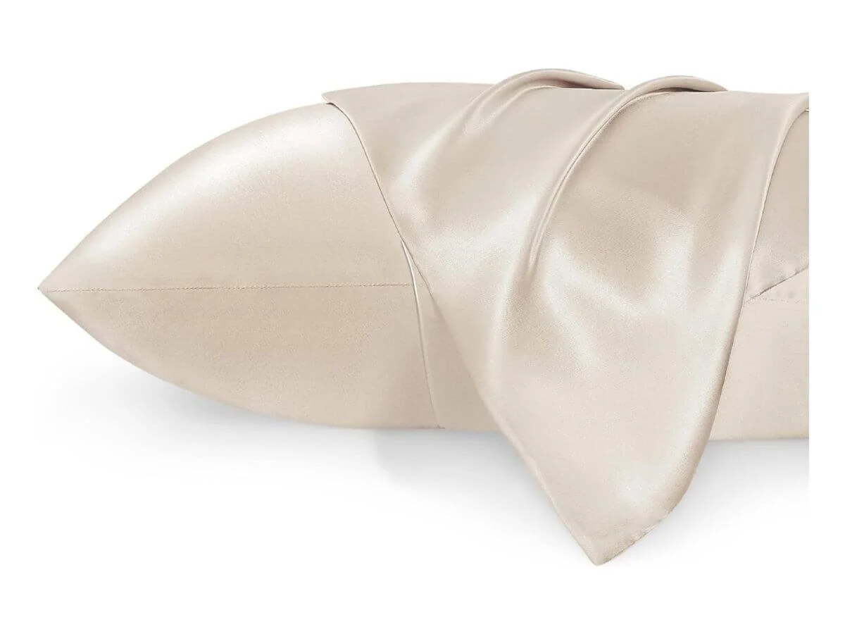 Smooth silk pillowcase draped over pillow in soft champagne color.