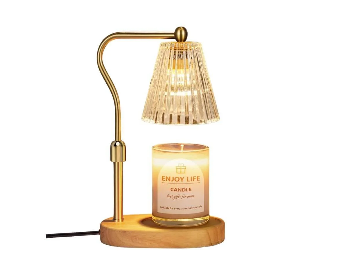 Gold candle warmer lamp with glass shade heating a scented candle on wooden base.