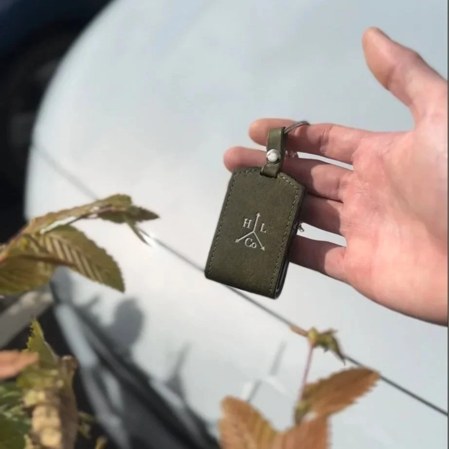 Green leather key cover held in front of Polestar car