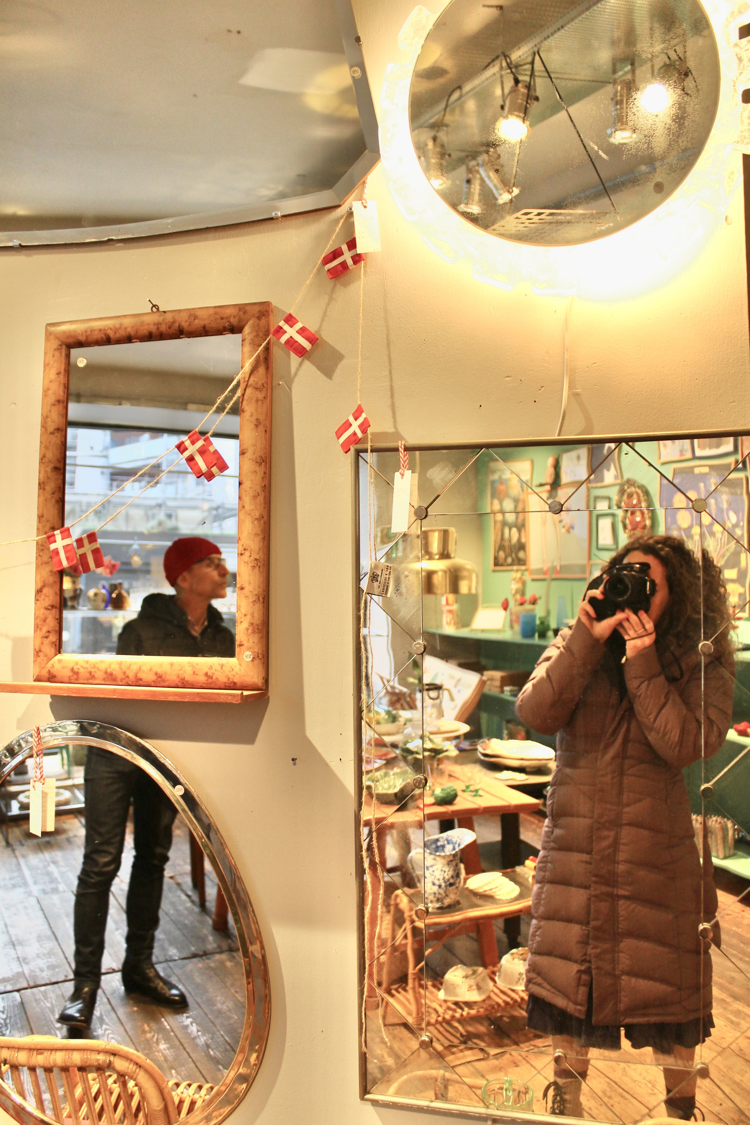Shop interior with a wall of mirrors and two shoppers reflected in them