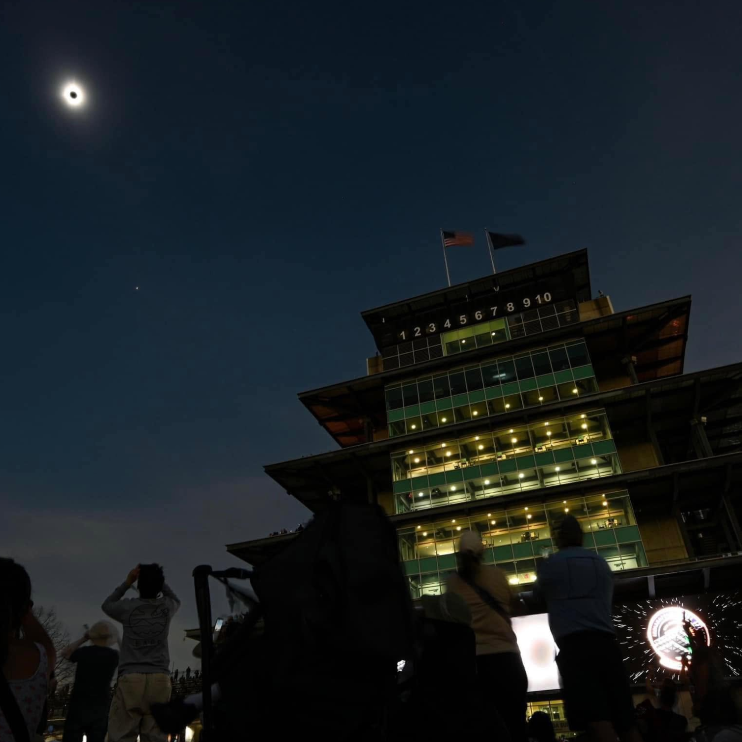 Solar eclipse above an illuminated racetrack tower
