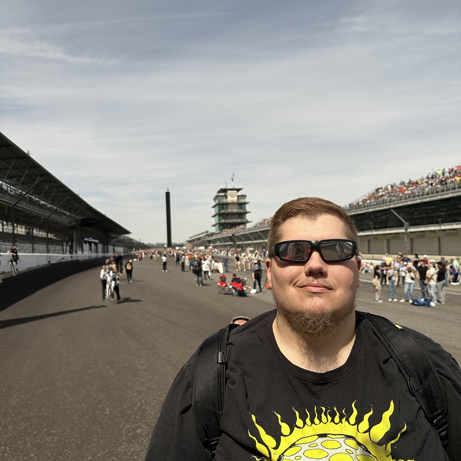 Man wearing sunglasses beside a racetrack grandstand