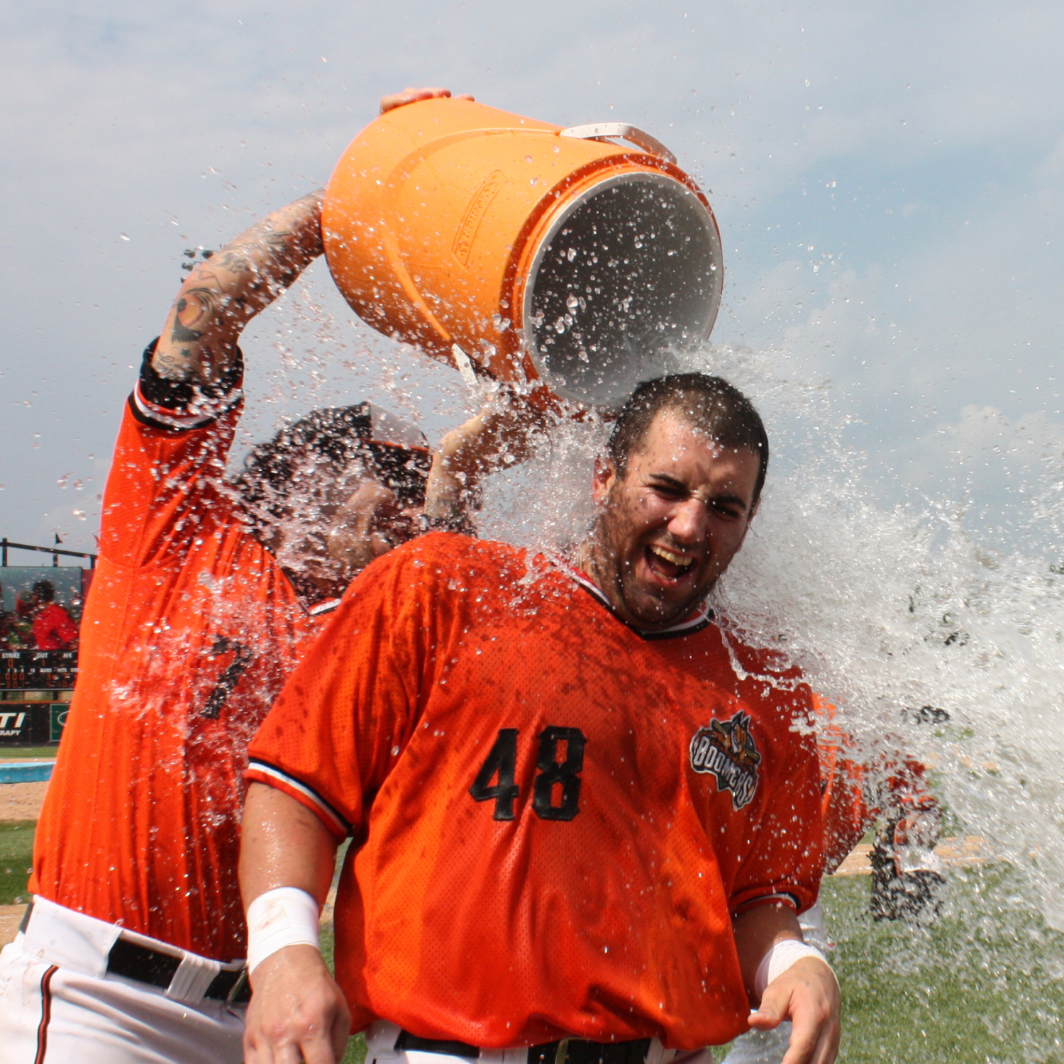 Teammate pouring a water cooler over a baseball player