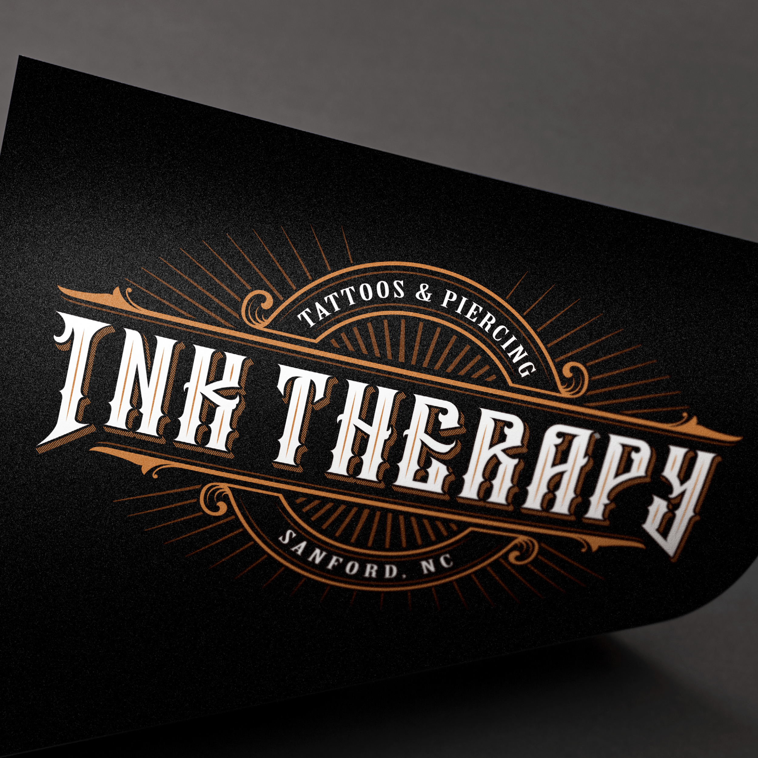 Logo for Ink Therapy featuring ornate text and decorative lines, advertising tattoos and piercing services in Sanford, North Carolina.