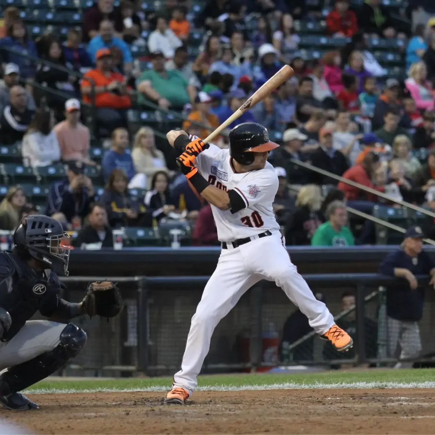Baseball player in a white uniform swinging at a pitched ball.