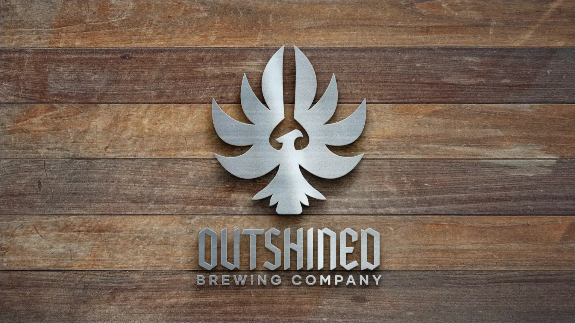 Outshined Brewing Company metal logo mounted on wood.
