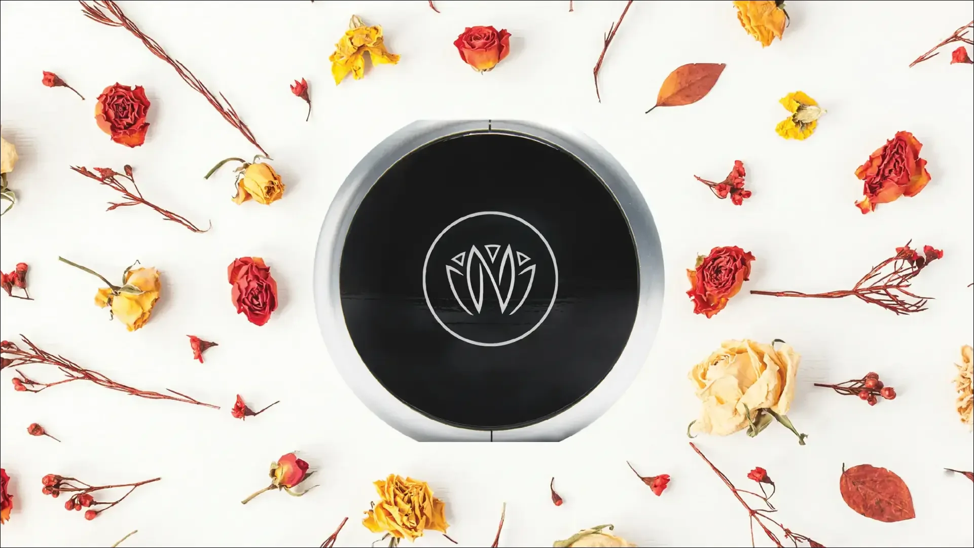Black-and-white coffee cup surrounded by dried yellow, orange, and red flowers.