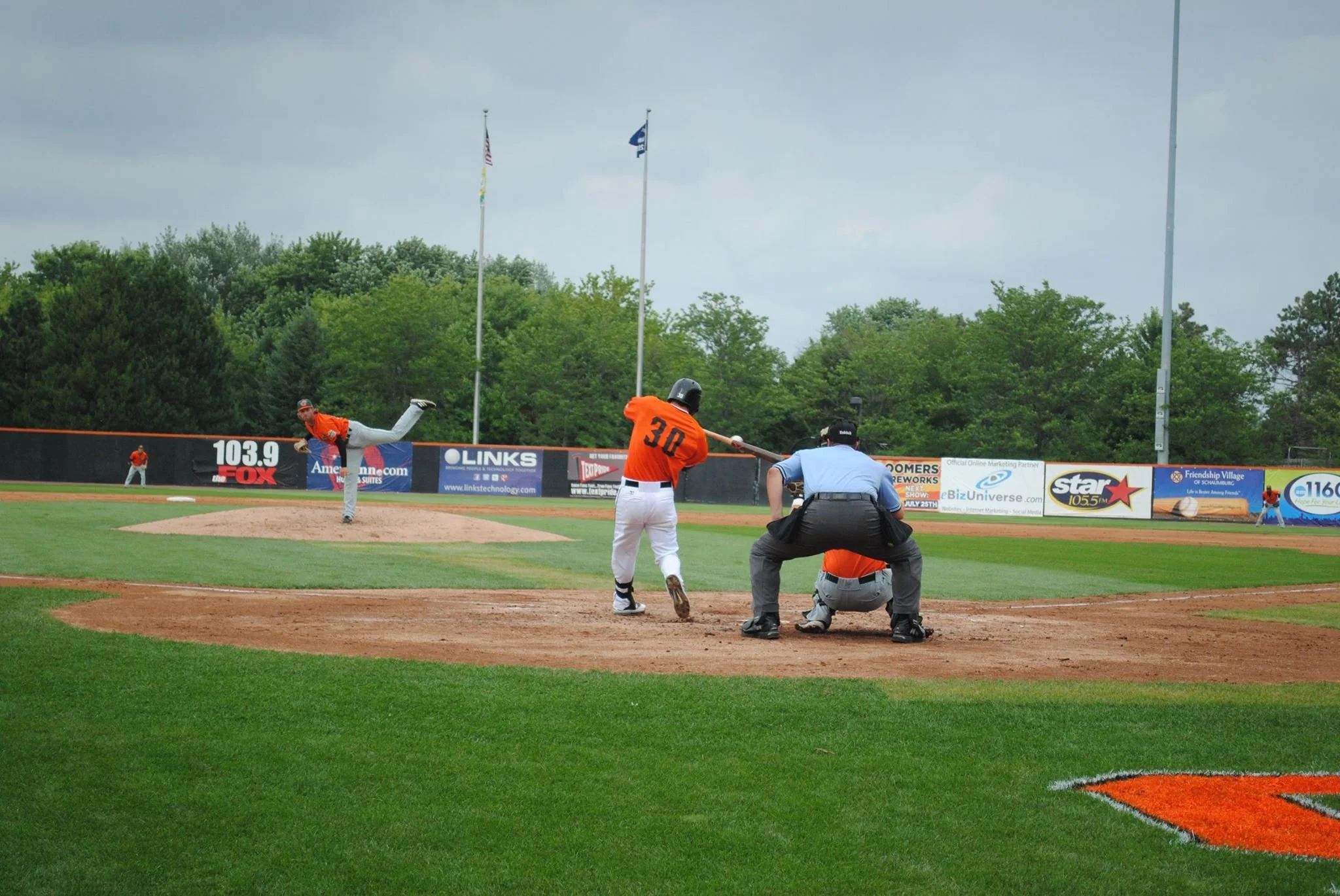 Baseball game moment with player sliding into home plate as catcher attempts a tag, with umpire watching closely.