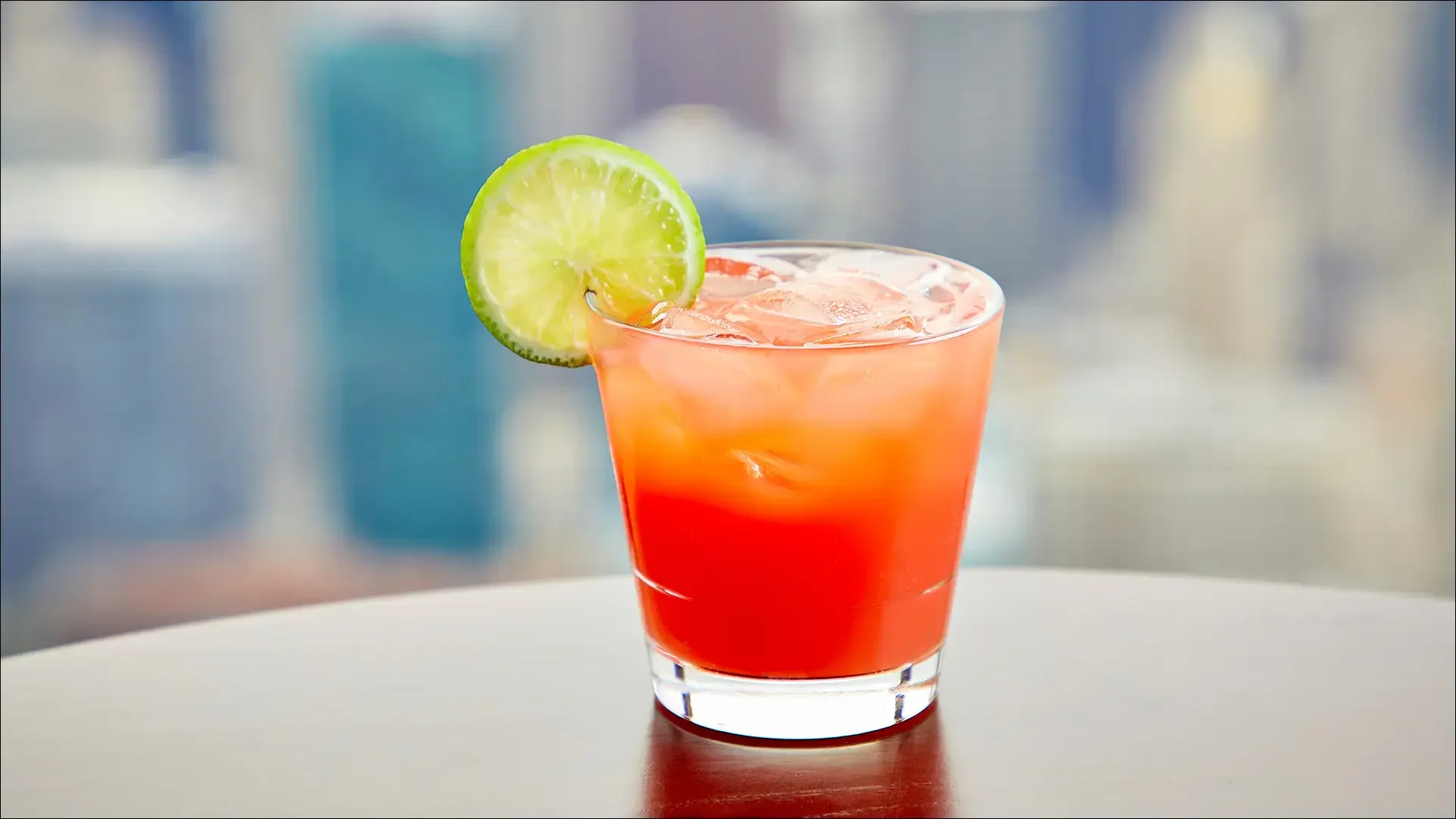 Red-orange cocktail with lime garnish
