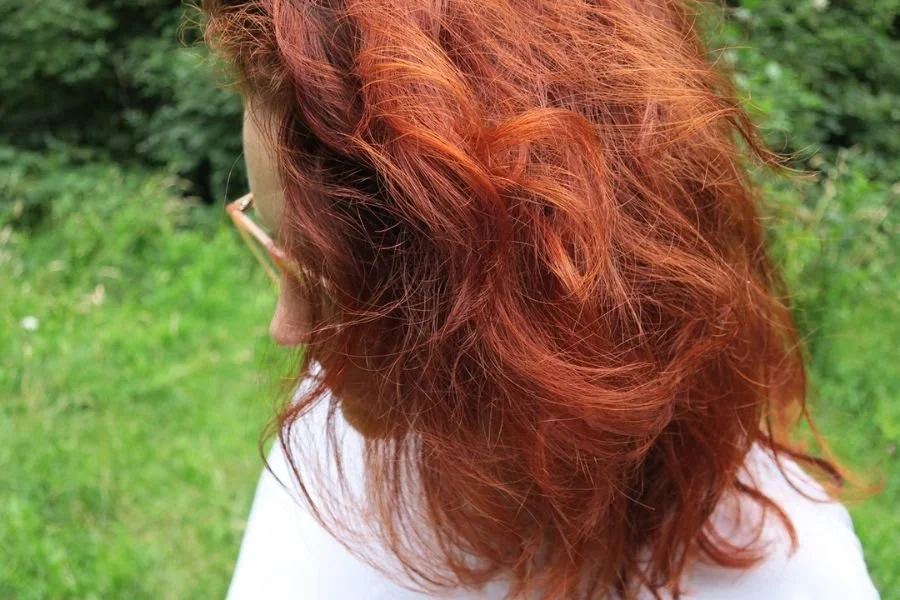 Susannah looking shyly downward, her red wavy hair hiding her face