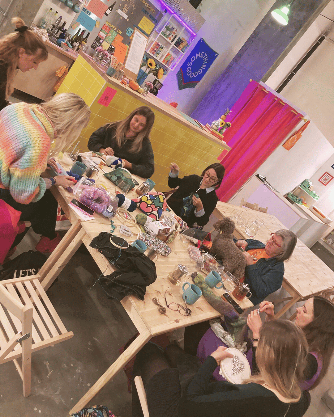 Small group of people sitting around tables at a Loose Threads craft gathering in London, quietly making projects together in a calm, low-pressure and supportive creative space.