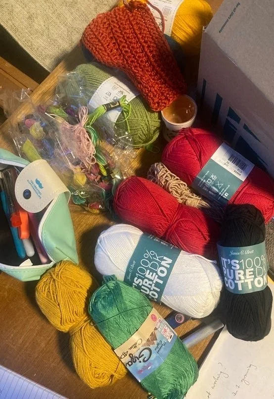 Messy jumble of crochet yarn, hooks, scissors and test scraps