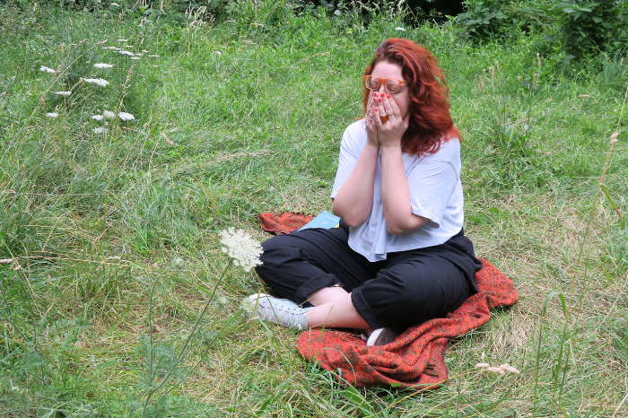 Gutsy founder Susannah Worth sitting in a park with eyes closed and hands over her face, expressing frustration with traditional confidence advice that often doesn’t work for shy or socially anxious people.