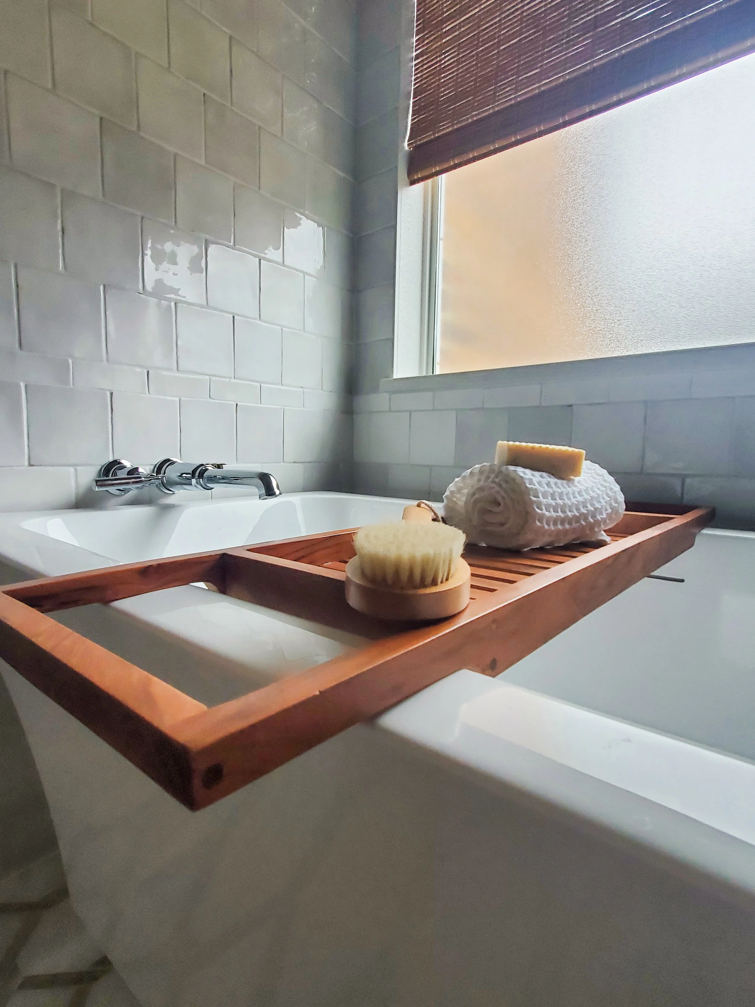 A  freestanding tub with a polished chrome wall mounted tub faucet in a Primary Bathroom in McKinney, Texas. Interior Design by Samantha Leonard Designs