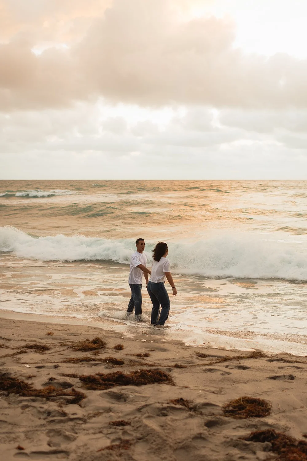couple walks along sunrise beach engagement