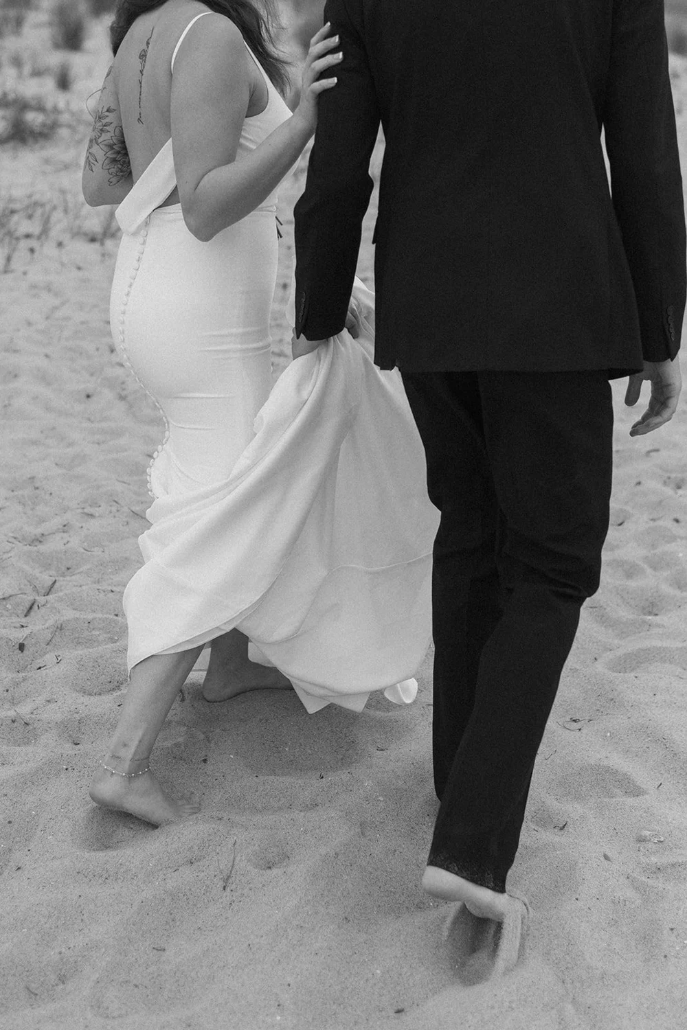 couple holds hands walking on beach