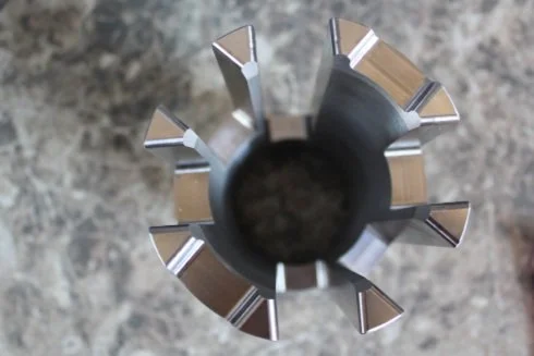 Top view of a metal cutting tool with sharp edges on a textured surface
