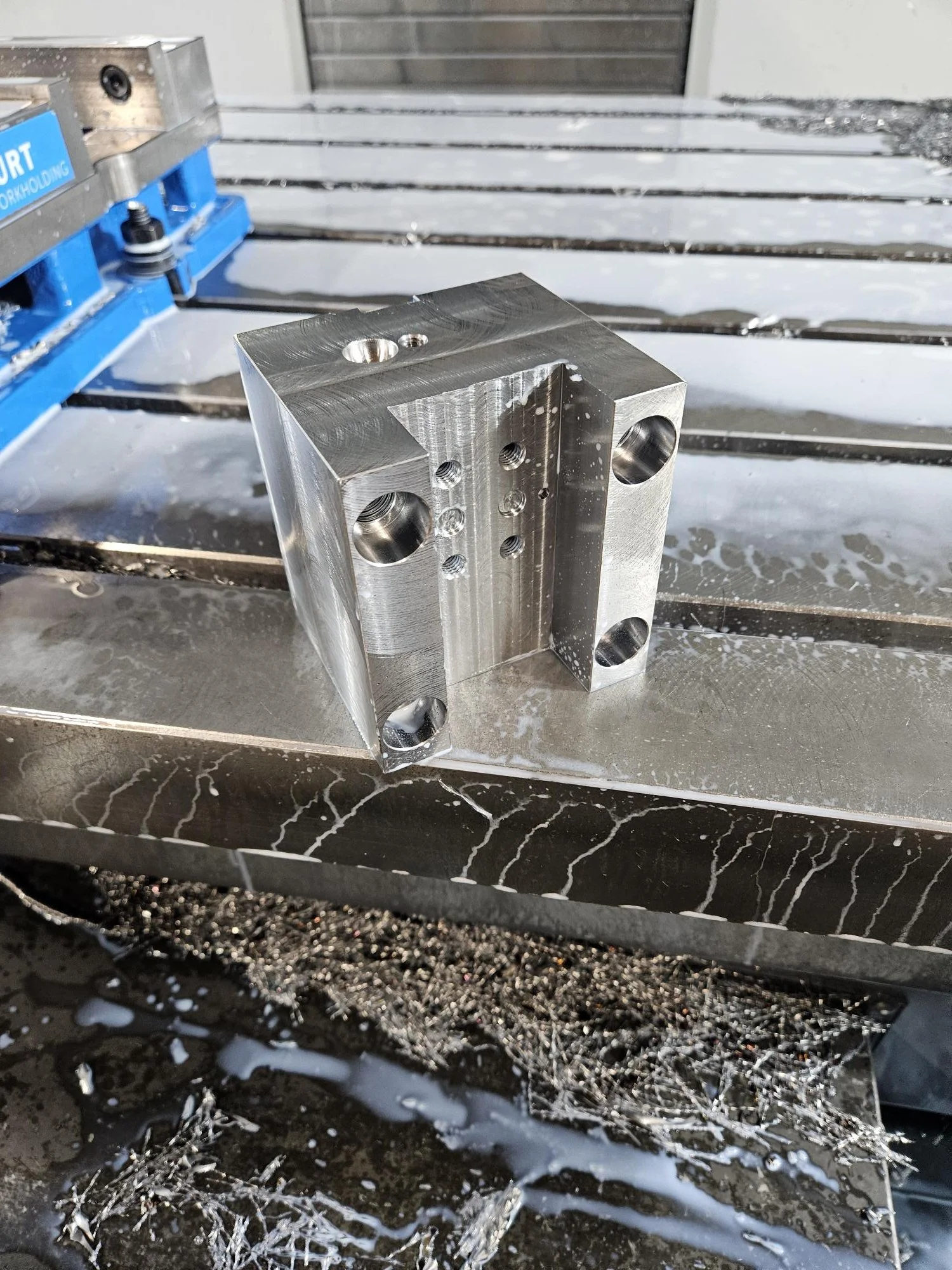 Machined metal block with holes on milling machine table