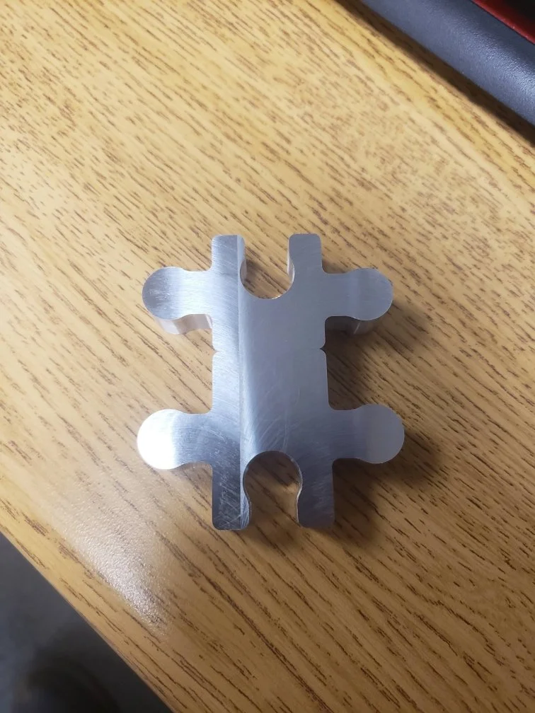 Metallic puzzle piece shape on wooden surface