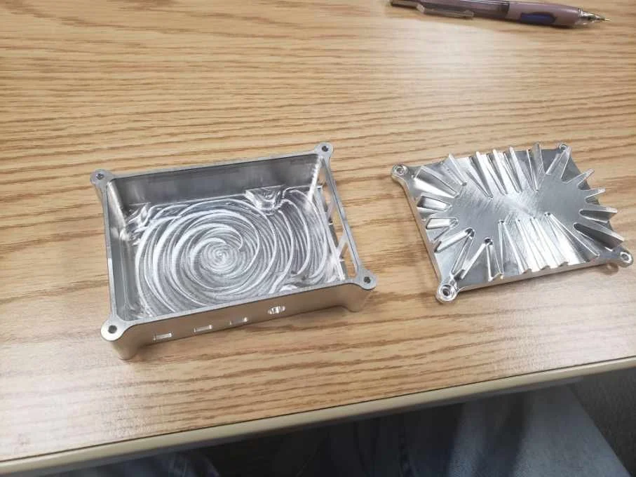 CNC-machined aluminum housing with cover on a wooden table