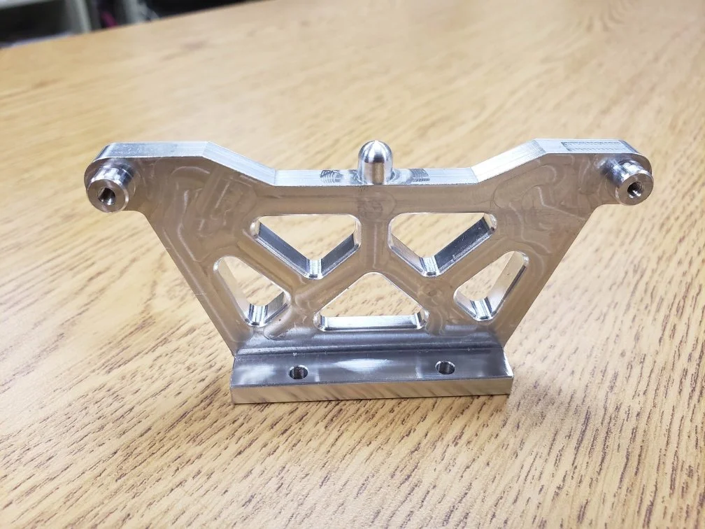 Metal bracket with geometric cutouts on wooden surface