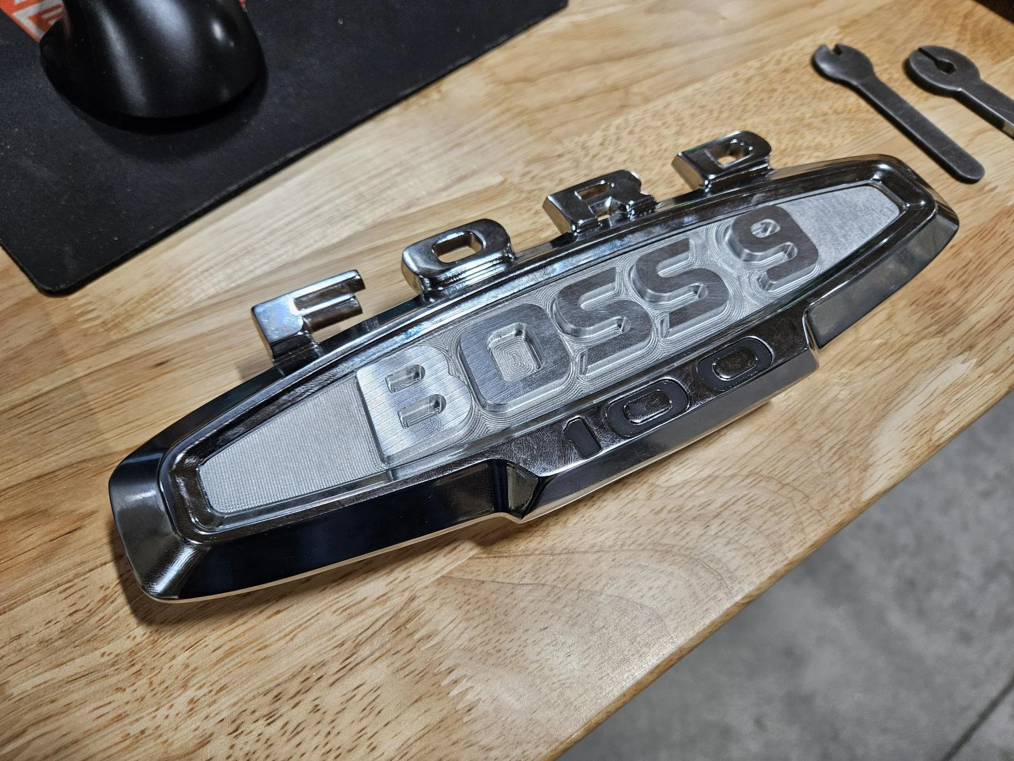 Ford Boss 9 100 emblem on wooden surface with tools