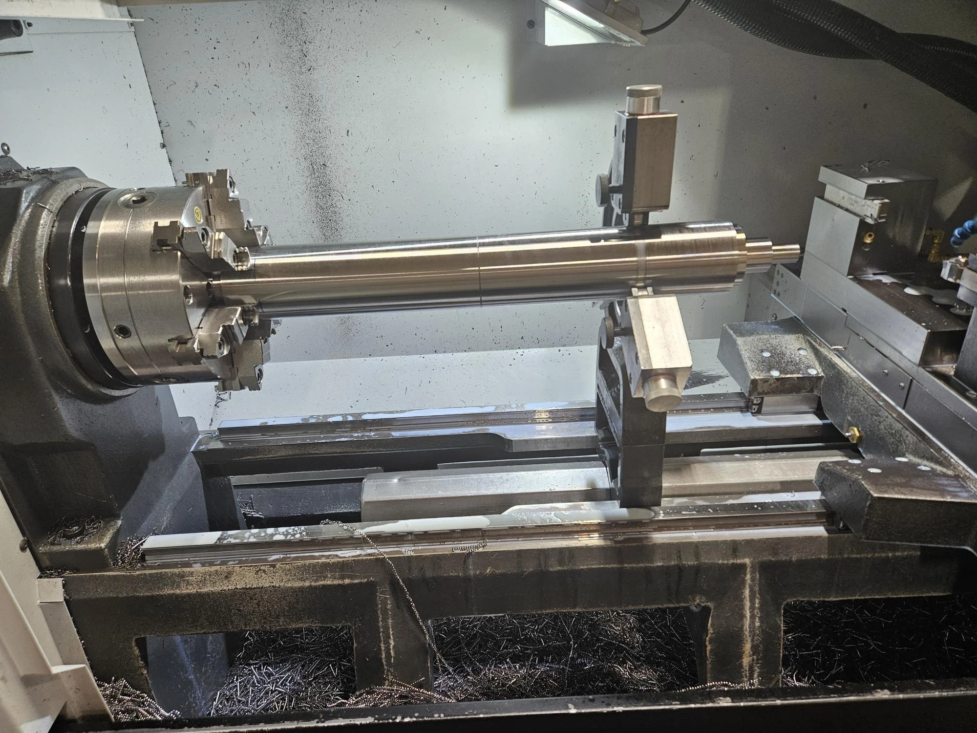 CNC lathe machine with a metal workpiece being machined.
