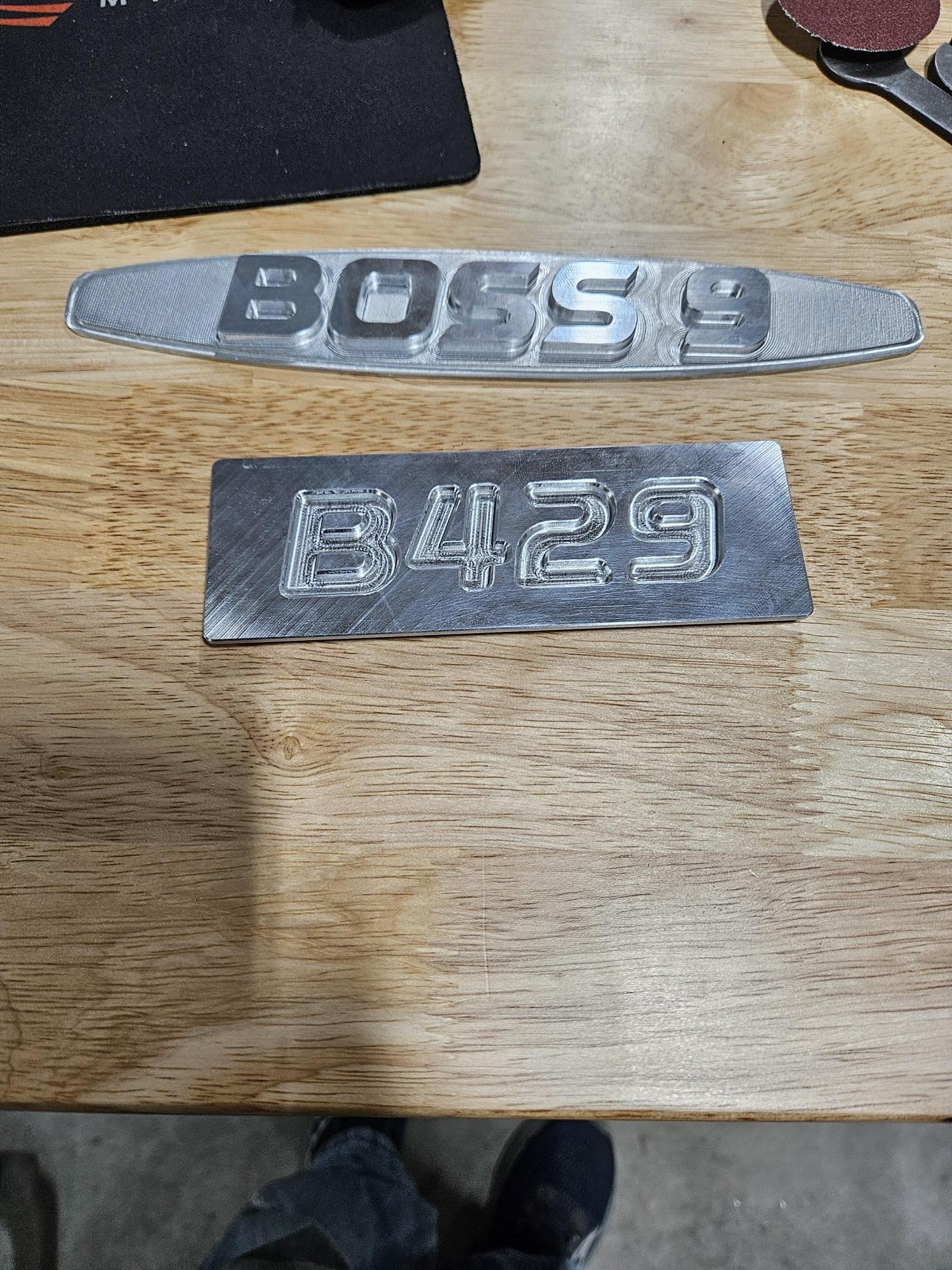 Metal plates on a wooden surface with engravings reading 'BOSS 9' and 'B429'.