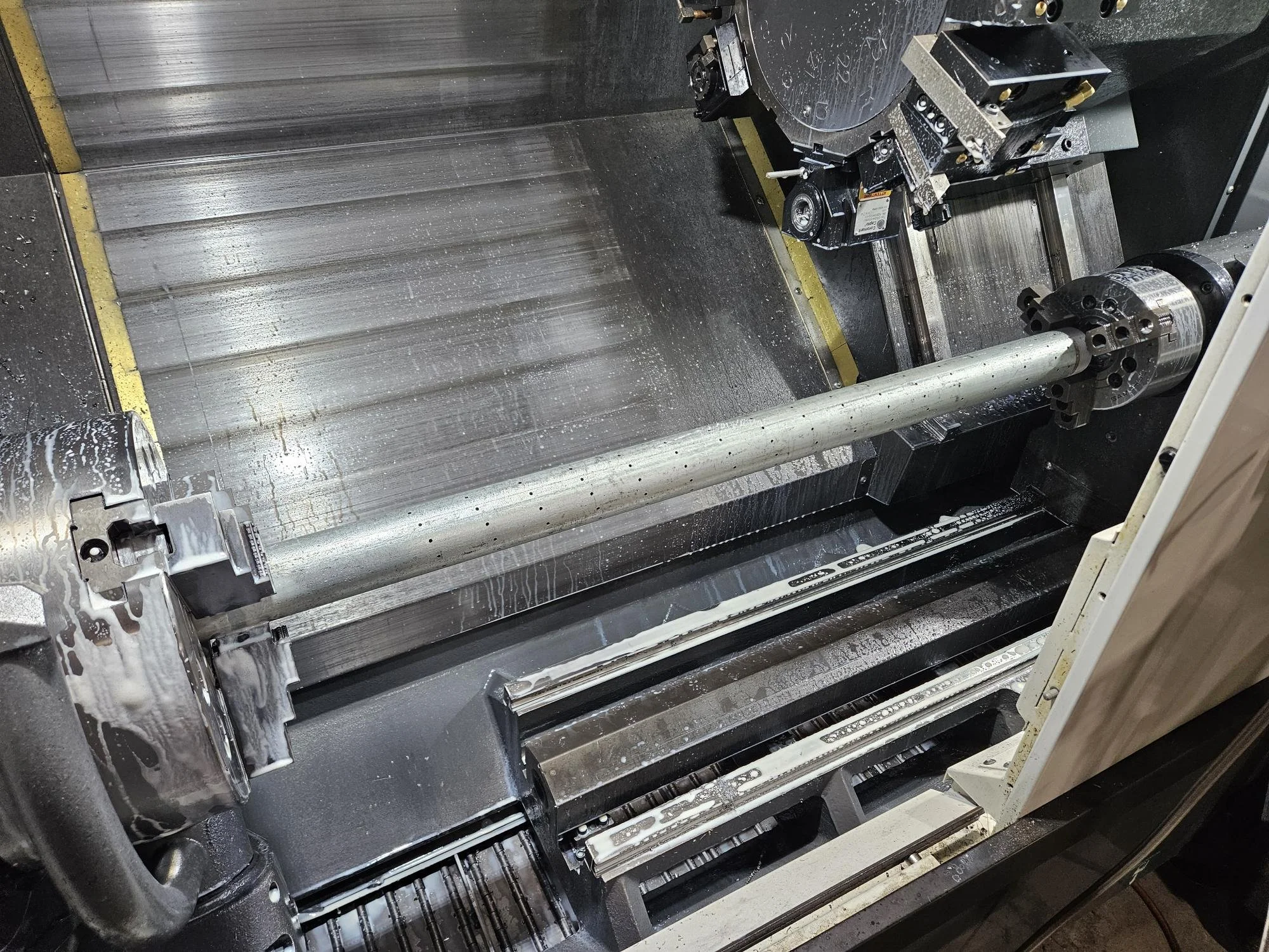 CNC lathe machine with a metal rod being machined inside.