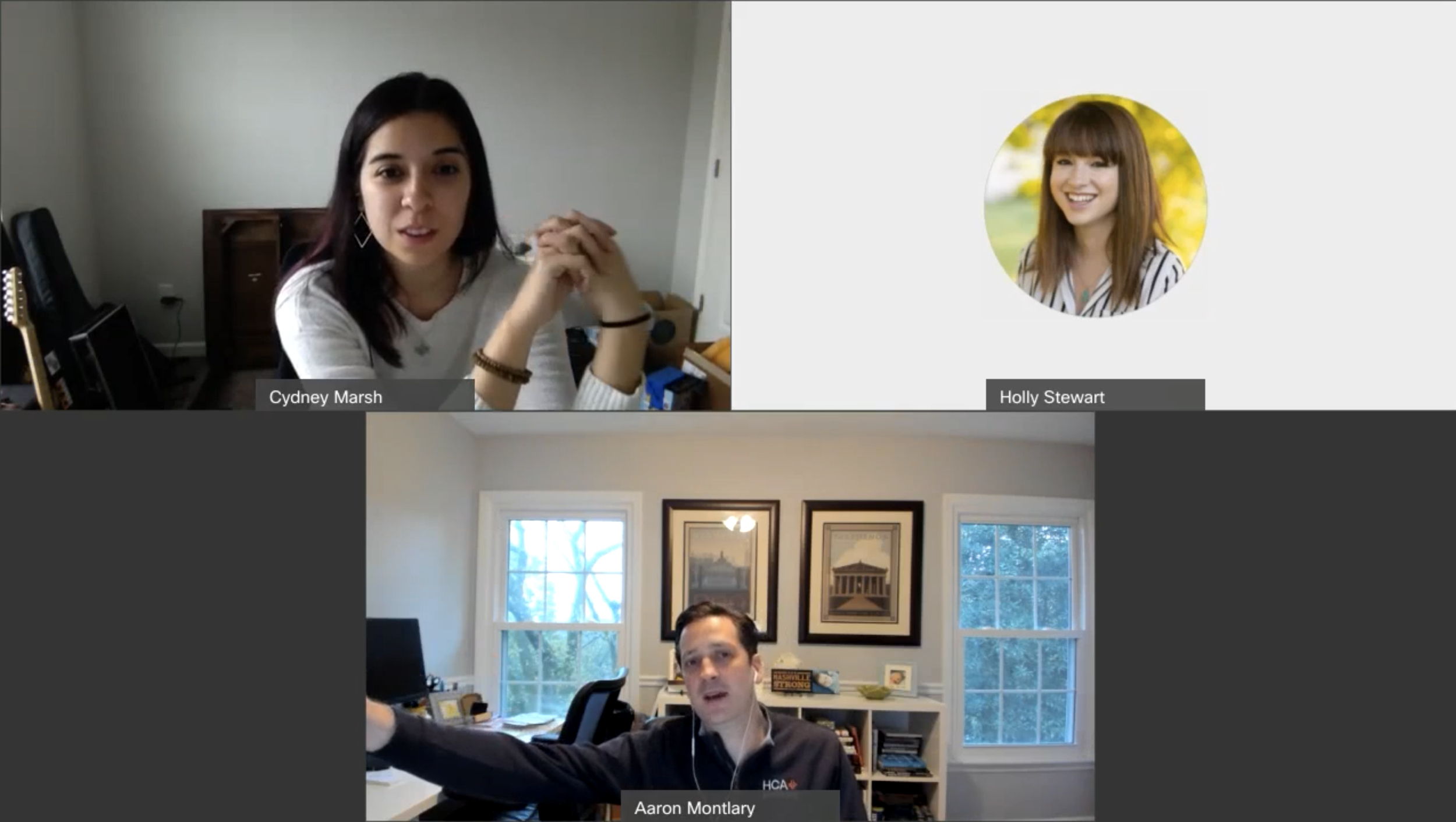 A virtual meeting with three participants, two women and one man. The woman in the upper left has dark hair and is wearing a white top, the woman in the upper right has light brown hair and is smiling, and the man in the lower center has dark hair and is wearing a dark jacket in a home office with framed pictures and large windows.