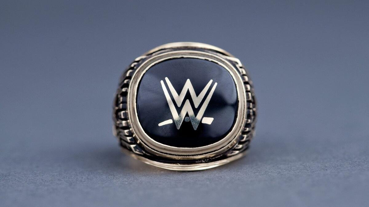 Close-up of a silver WWE championship ring with a black Faceplate featuring the WWE logo.
